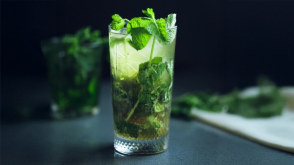 Mojito korkeaan lasiin tehtynä, jossa runsaasti minttua ja limelohkoja.