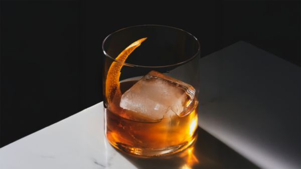Drinkkikoulussa valmistunut tyylikäs Old Fashioned cocktail klassisella appelsiininkuori koristeella.